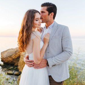 Boyfriend kissing his girlfriend on teh cheek by the water
