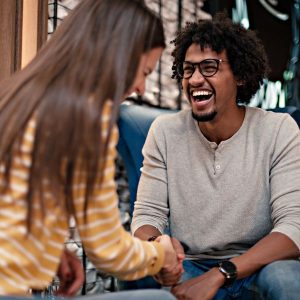 Guy and girl shaking hands and laughing when meeting for the first time